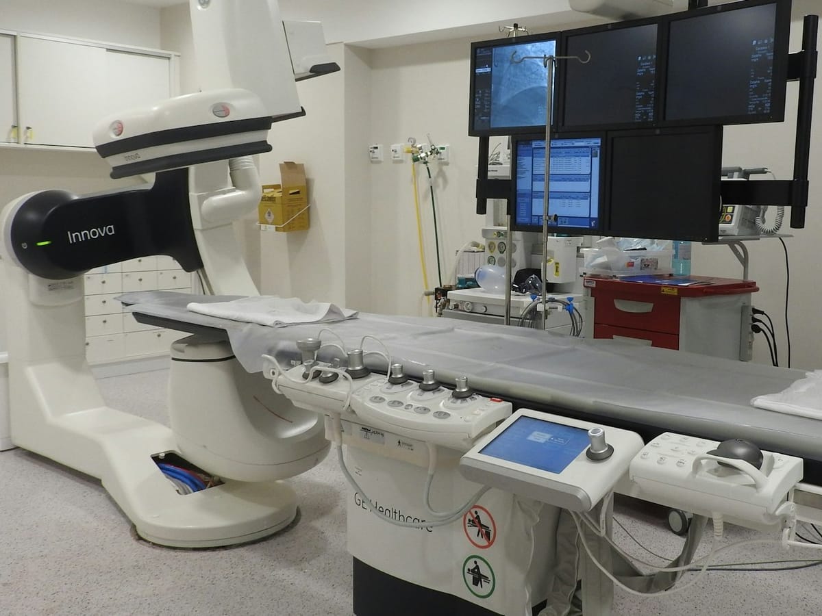 Robotic surgical system in a hospital operating room with medical staff preparing for a procedure.